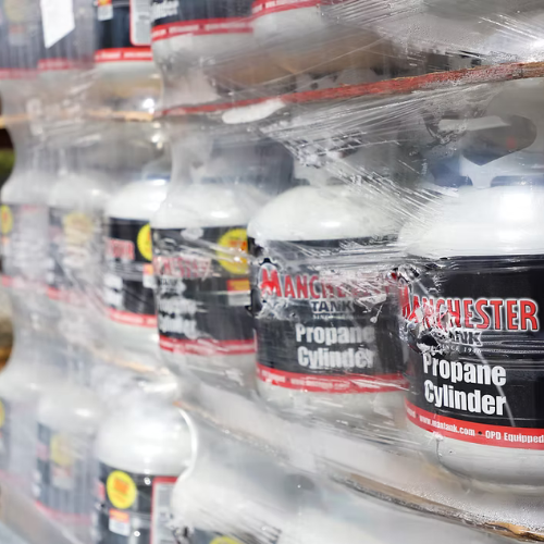 Stack of Manchester propane cylinders wrapped in plastic on a pallet, labels visible, conveying a sense of industrial supply and storage.